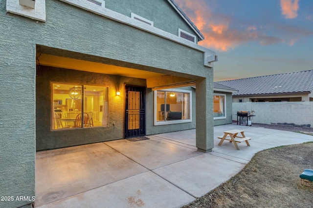 rear view of house featuring stucco siding, fence, and a patio area