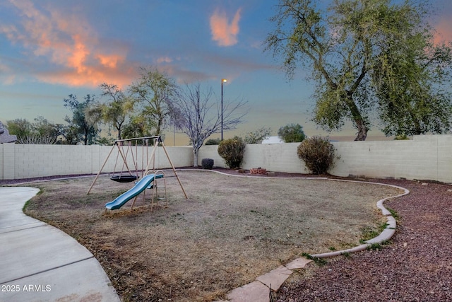 yard at dusk with a playground and a fenced backyard