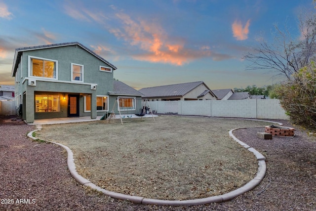 rear view of property with stucco siding, a patio, and a fenced backyard