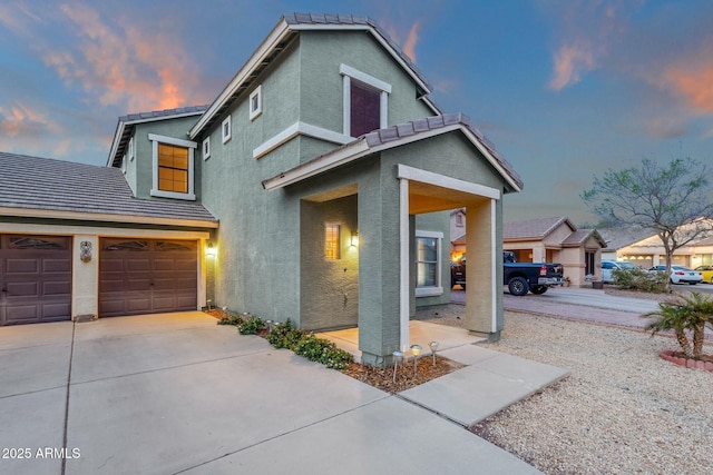 view of front of home with a tiled roof, stucco siding, driveway, and a garage