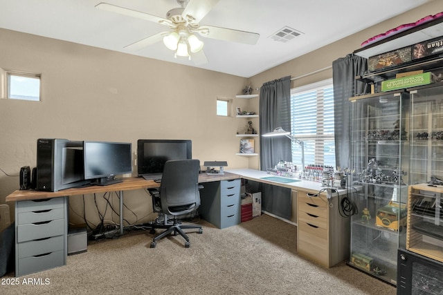 office space with visible vents, light colored carpet, and a ceiling fan