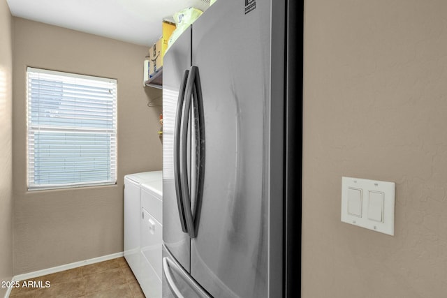 laundry area with laundry area, plenty of natural light, washing machine and dryer, and light tile patterned floors