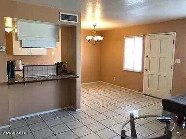 kitchen with a notable chandelier, hanging light fixtures, kitchen peninsula, and light tile patterned flooring