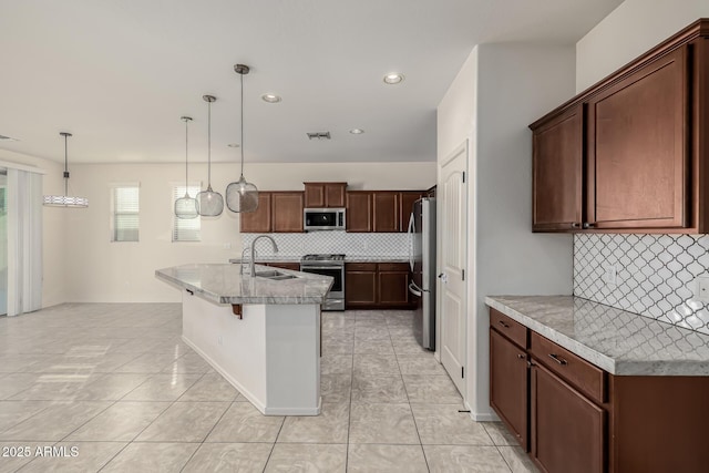 kitchen with a kitchen bar, stainless steel appliances, tasteful backsplash, pendant lighting, and sink