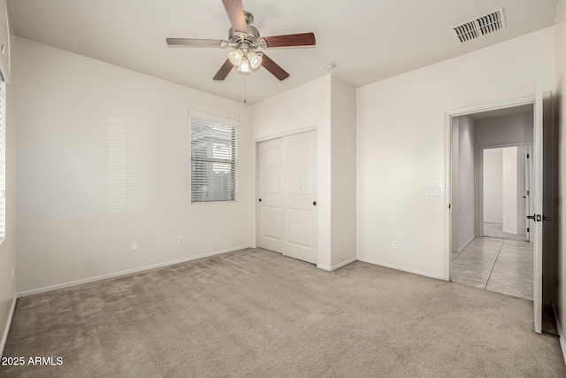 unfurnished bedroom featuring light carpet, ceiling fan, and a closet