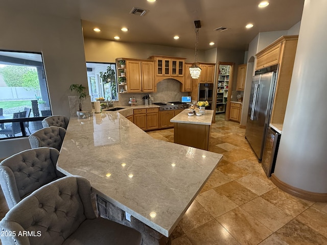 kitchen featuring visible vents, a peninsula, stainless steel appliances, and decorative backsplash