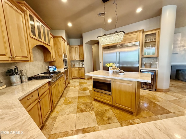 kitchen featuring tasteful backsplash, a kitchen island, beverage cooler, built in appliances, and light countertops