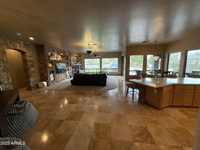 kitchen featuring a fireplace, arched walkways, light countertops, a notable chandelier, and open floor plan