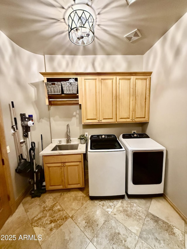 washroom with baseboards, visible vents, washing machine and clothes dryer, cabinet space, and a sink