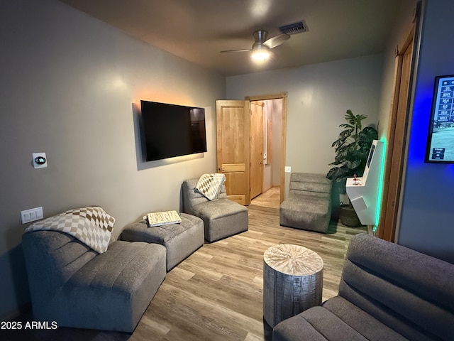 living room with visible vents, ceiling fan, and wood finished floors