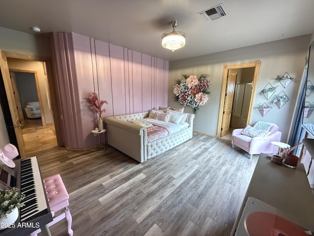 bedroom with visible vents, baseboards, and wood finished floors