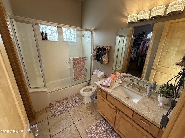 bathroom featuring tile patterned flooring, a walk in closet, bath / shower combo with glass door, toilet, and vanity