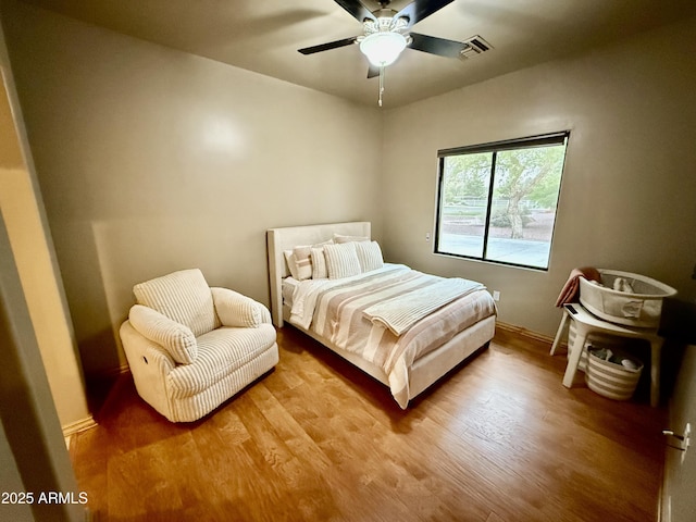 bedroom with visible vents, ceiling fan, baseboards, and wood finished floors