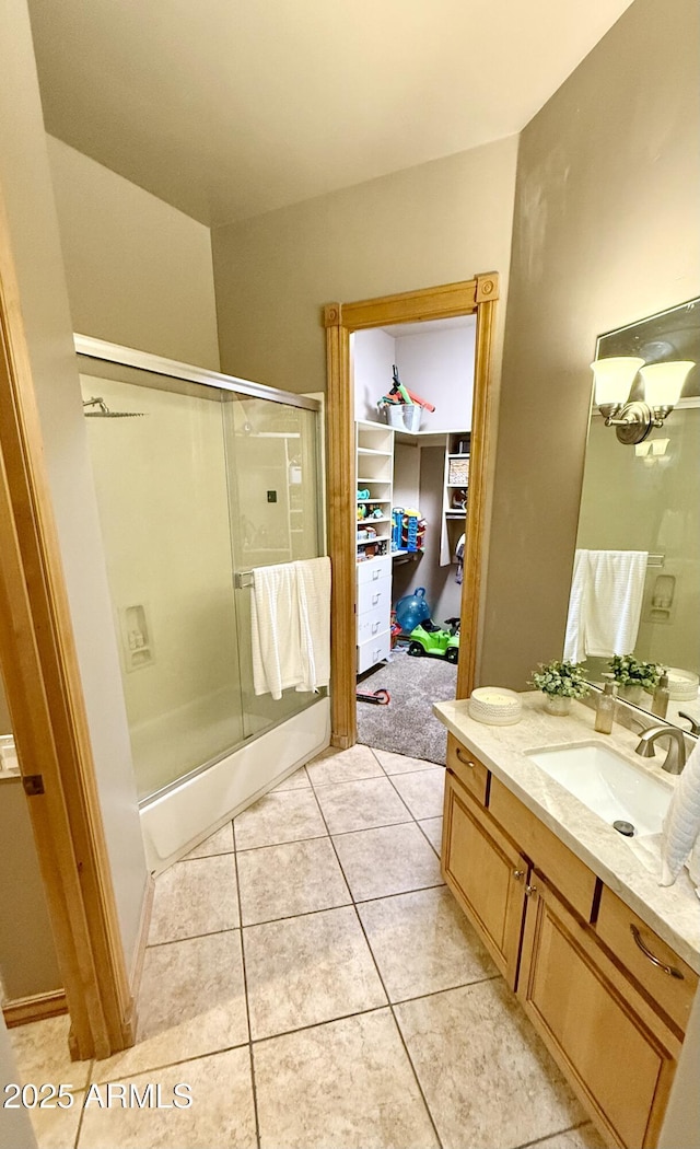 bathroom featuring a shower with shower door, vanity, and tile patterned flooring