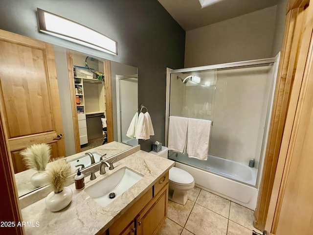 full bath with tile patterned flooring, toilet, vanity, and shower / bath combination with glass door