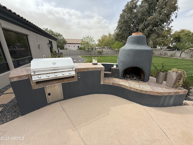 view of patio / terrace featuring an outdoor fireplace, an outdoor kitchen, a grill, and fence