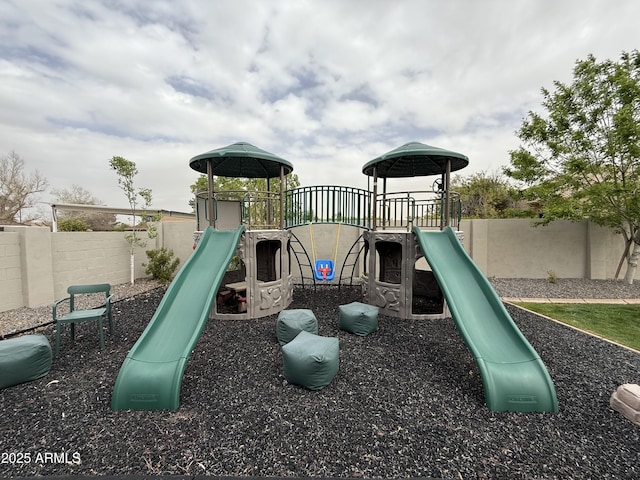 community jungle gym featuring a fenced backyard