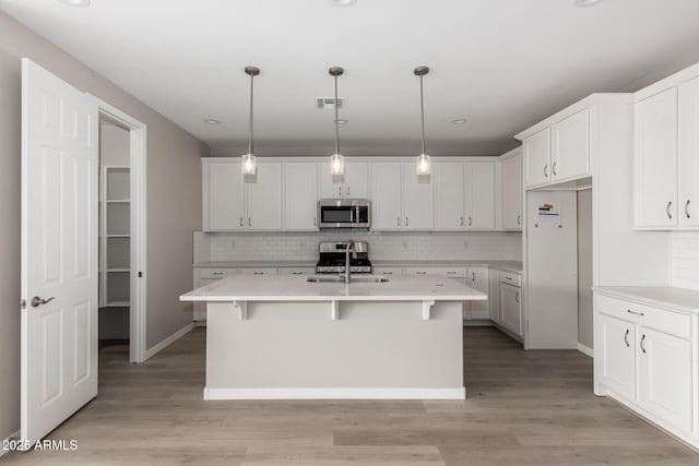 kitchen with a kitchen island with sink, sink, white cabinets, and stainless steel appliances