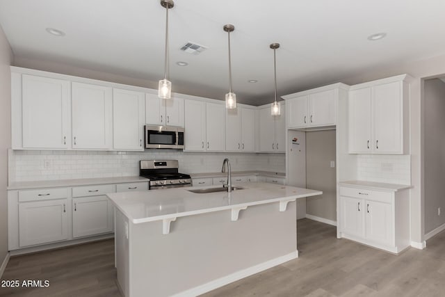 kitchen with stainless steel appliances, white cabinetry, a kitchen island with sink, and sink