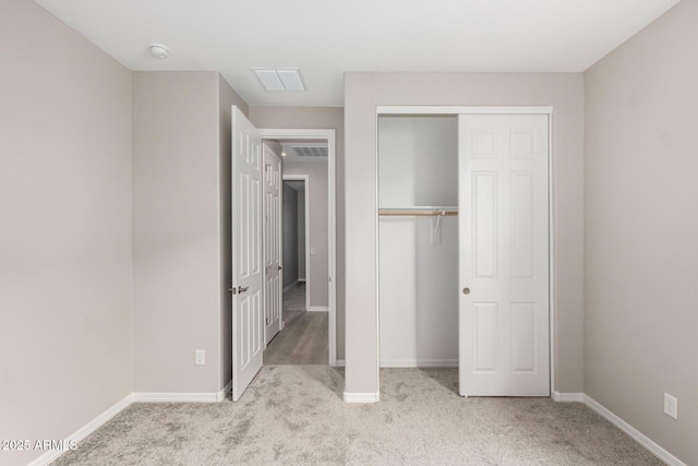 unfurnished bedroom with light carpet and a closet