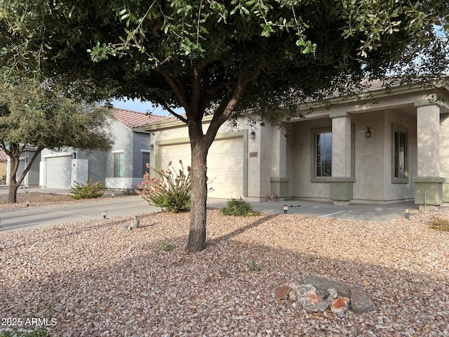 view of front of house with a garage, a tile roof, concrete driveway, and stucco siding