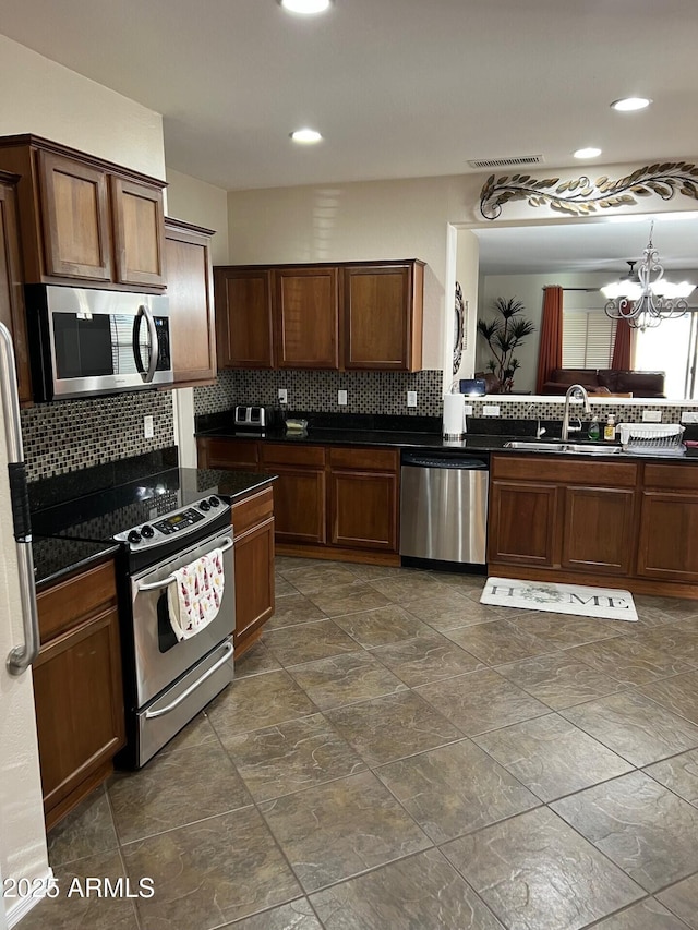 kitchen with visible vents, dark countertops, appliances with stainless steel finishes, a sink, and backsplash