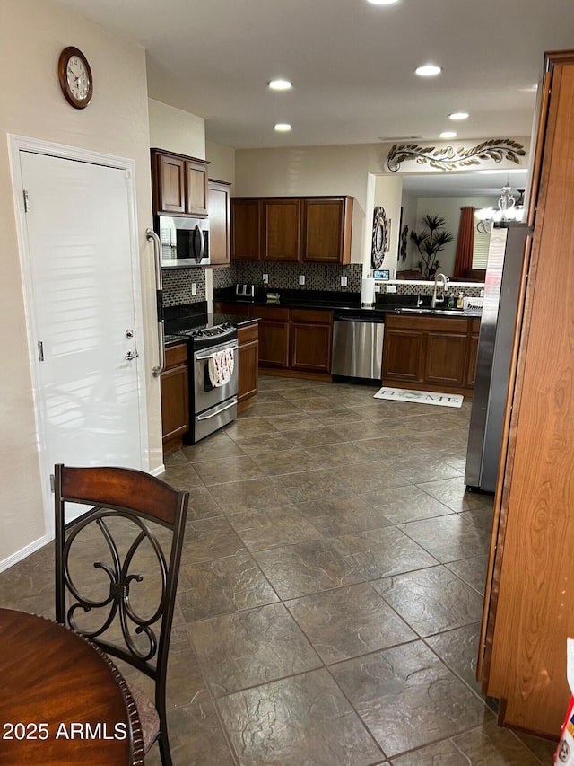 kitchen with tasteful backsplash, dark countertops, appliances with stainless steel finishes, a sink, and recessed lighting