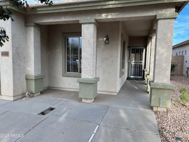 view of exterior entry with a patio area and stucco siding