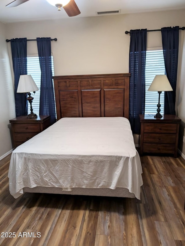 bedroom with ceiling fan, dark wood-style flooring, visible vents, and baseboards