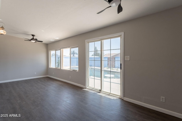 empty room with a ceiling fan, baseboards, and dark wood finished floors