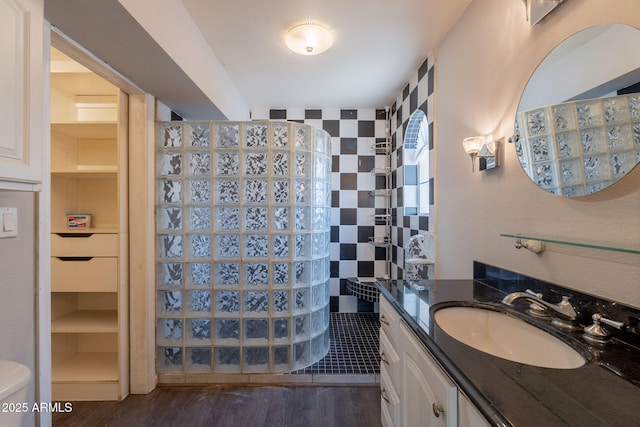 bathroom featuring wood finished floors, vanity, and a walk in shower