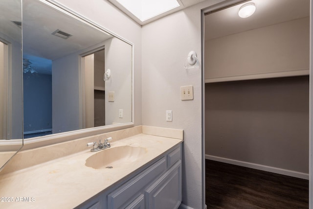 bathroom with baseboards, visible vents, wood finished floors, and vanity