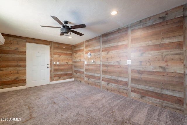 spare room featuring a ceiling fan, carpet flooring, wood walls, and recessed lighting