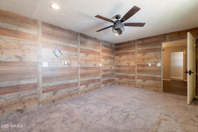 carpeted empty room with a ceiling fan, wooden walls, and recessed lighting