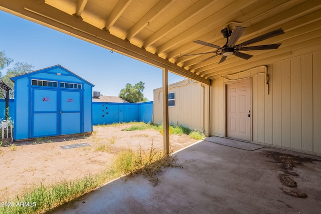 view of patio with an outdoor structure, ceiling fan, a fenced backyard, and a storage unit