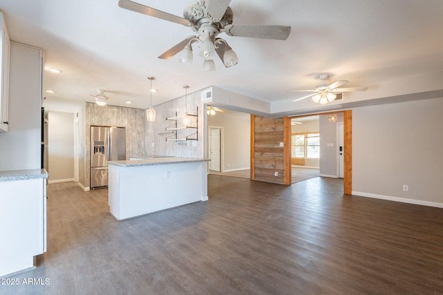 kitchen featuring a peninsula, stainless steel refrigerator with ice dispenser, ceiling fan, open floor plan, and baseboards