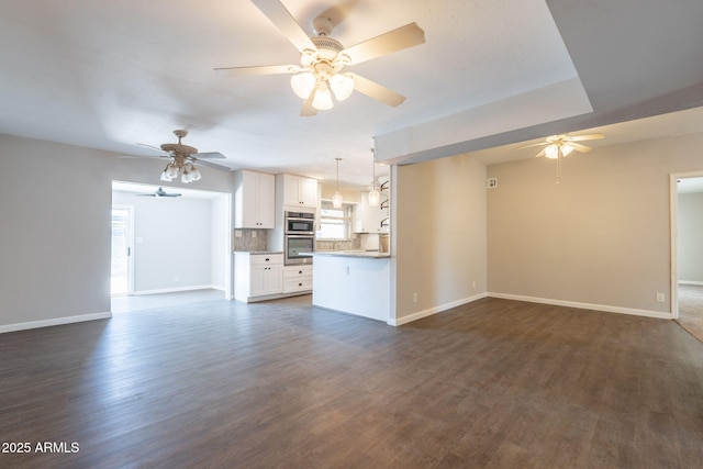 unfurnished living room with dark wood-style floors, baseboards, and a ceiling fan