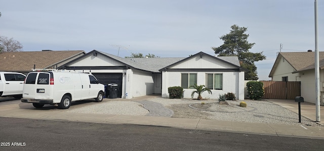 ranch-style home with a garage, concrete driveway, and fence