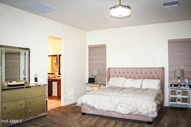 bedroom featuring connected bathroom and dark carpet