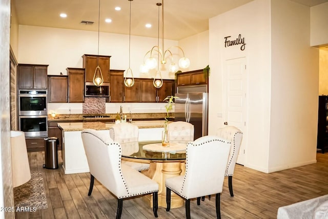 dining area with a high ceiling, sink, and light hardwood / wood-style floors