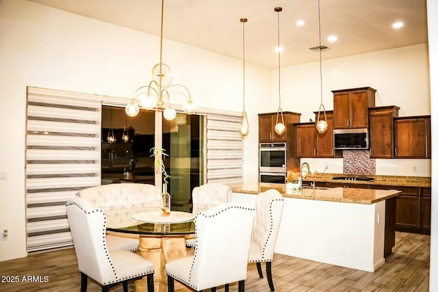 dining area featuring sink, wood-type flooring, a chandelier, and a high ceiling