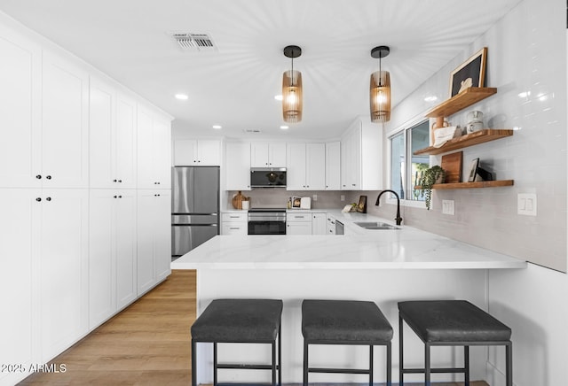 kitchen featuring appliances with stainless steel finishes, sink, white cabinets, and kitchen peninsula