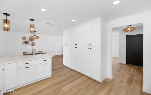 kitchen featuring pendant lighting, white cabinets, and light hardwood / wood-style flooring