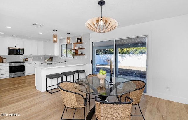 dining area featuring a chandelier, sink, and light wood-type flooring