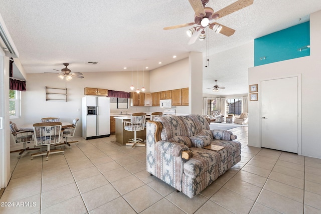 tiled living room with ceiling fan, a textured ceiling, and high vaulted ceiling