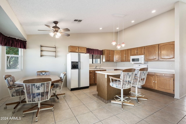 kitchen featuring white appliances, a kitchen breakfast bar, hanging light fixtures, vaulted ceiling, and a kitchen island