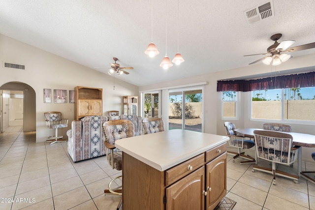 kitchen featuring a center island, lofted ceiling, hanging light fixtures, light tile patterned floors, and a textured ceiling