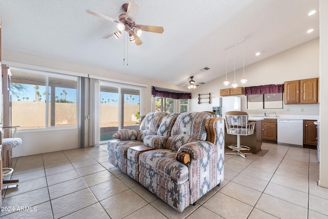 tiled living room featuring a textured ceiling, ceiling fan, sink, and vaulted ceiling