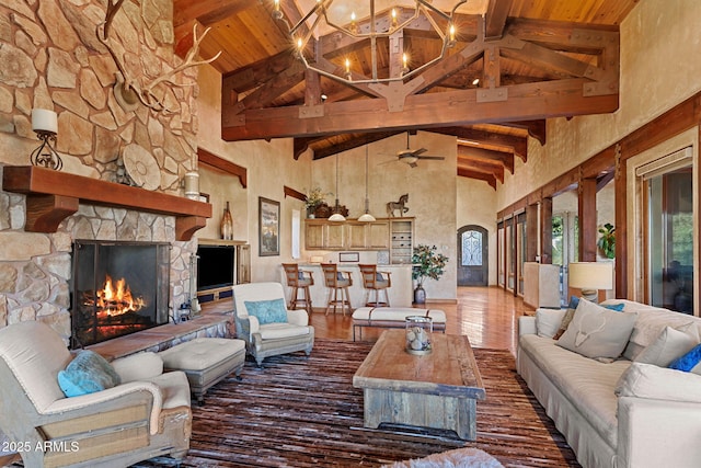 living room featuring ceiling fan with notable chandelier, beamed ceiling, a fireplace, and wood ceiling