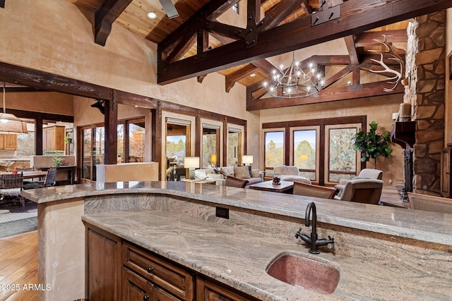 kitchen featuring light stone countertops, beam ceiling, wood ceiling, and sink